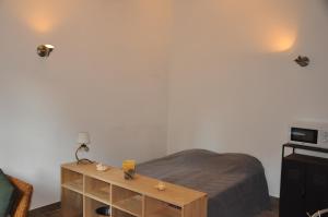 1 dormitorio con cama y mesa de madera en location studio meublé avec jardin, en Sorgues