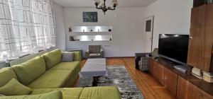 uma sala de estar com um sofá verde e uma televisão de ecrã plano em Fortress View Apartment em Belogradchik