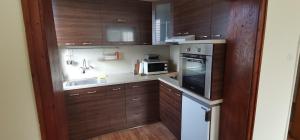 una pequeña cocina con armarios de madera y microondas en Fortress View Apartment, en Belogradchik
