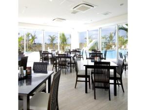a dining room with tables and chairs and windows at HOTEL GranView Garden OKINAWA - Vacation STAY 44964v in Tomigusuku
