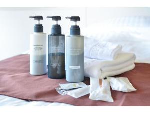 three bottles ofodorizers and towels on a bed at HOTEL GranView Garden OKINAWA - Vacation STAY 44964v in Tomigusuku