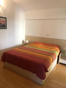 a bedroom with a bed with a striped blanket at BMV TRIPLE ROOM WITH BALCONY in Sveti Stefan