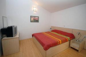 a small bedroom with a bed and a tv at BMV TRIPLE ROOM WITH BALCONY in Sveti Stefan