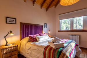 1 dormitorio con 1 cama, 1 lámpara y 2 ventanas en Hostería Bajo Cero, en Villa La Angostura