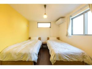 2 camas en una habitación con paredes amarillas y ventana en rakuna Inn Dou-sasazuka - Vacation STAY 47231v, en Tokio