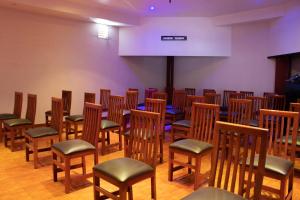 una habitación con filas de sillas de madera y un escenario en Hotel Palass en Toluca