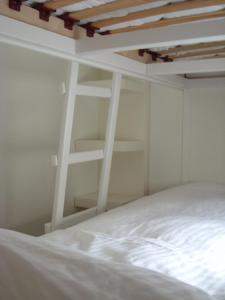 een wit bed in een witte kamer met een ladder bij Luxe Strandhuisje op het strand van Wijk aan Zee met wifi in Wijk aan Zee