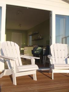 Dos mecedoras blancas sentadas en un porche en Luxe Strandhuisje op het strand van Wijk aan Zee met wifi, en Wijk aan Zee