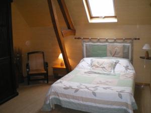 1 dormitorio con 1 cama, 1 silla y 1 ventana en le tilleul, en Caumont