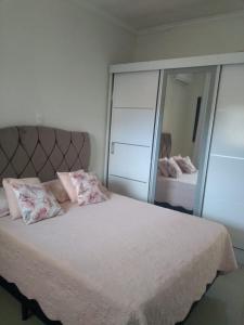 a bedroom with a large white bed with a mirror at Vila do Aconchego in Ubatuba