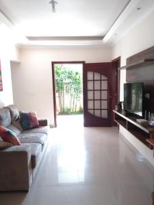 a living room with a couch and a television at Vila do Aconchego in Ubatuba