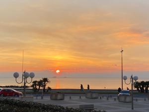 una puesta de sol sobre el océano con gente caminando por la playa en Capveo en Pornichet