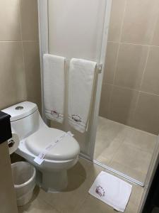 a bathroom with a toilet and a shower with towels at Hotel Palass in Toluca