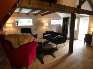 a living room with a red couch and a chair at Vakantieverblijf Perron 3 in Haarle