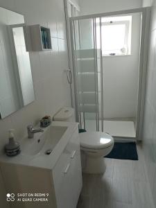 een witte badkamer met een toilet en een wastafel bij CASA do BATORÉU - BUARCOS 120 MT PRAIA in Figueira da Foz