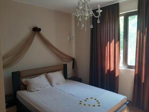 a bedroom with a white bed with a chandelier at Вила Мая 2 in Krayni Dol