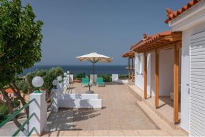 a patio with chairs and an umbrella and the ocean at Platy Sea View Lxs in Plati