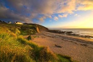 een strand met een huis op een heuvel naast de oceaan bij OA Surf Club in Bude