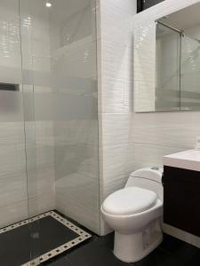 a white bathroom with a toilet and a shower at Hotel Regency Boutique La Feria in Bogotá