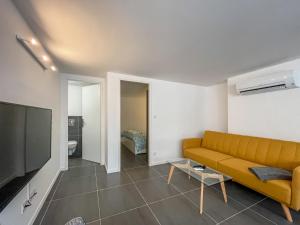 a living room with a yellow couch and a television at T2 tout équipé à 2 min de la plage ménage inclus 1 in Banyuls-sur-Mer