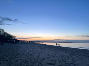 un gruppo di persone che camminano sulla spiaggia al tramonto di Blue Marina Gdańsk a Danzica