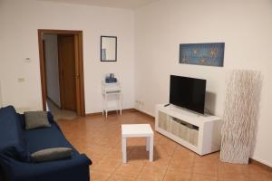un soggiorno con divano blu e TV di La Casa di Magiù a Terrasini