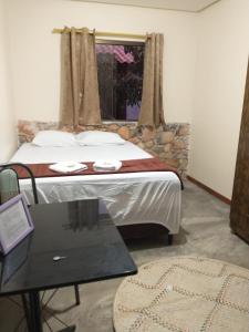 1 dormitorio con 1 cama con mesa y ventana en Chalés Vila Bela Vale do Capão en Vale do Capao