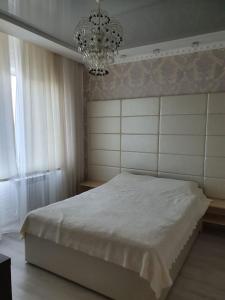 ein Schlafzimmer mit einem großen weißen Bett und einem Kronleuchter in der Unterkunft Apartment Viliamsa in Odessa