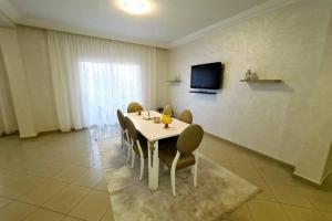 a dining room with a table and chairs and a tv at Appartement Haut Standing en plein centre ville in Agadir