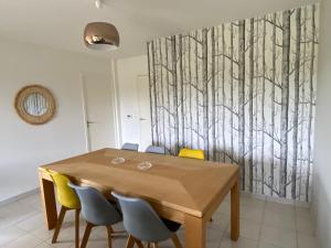 a dining room with a wooden table and yellow chairs at LOGEMENT en rdc Port Haliguen in Quiberon