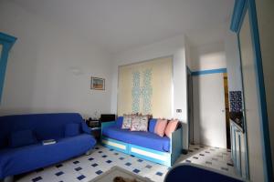 a living room with a blue couch and a bed at Dammusi al Tramonto in Pantelleria