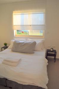 1 dormitorio con 1 cama blanca y ventana en צימר מול השקיעה, en Retamim