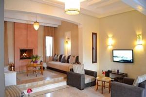a living room with a couch and a tv at Villa Selma avec piscine chauffée in Marrakesh