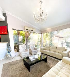 a living room with white furniture and a chandelier at Hotel das Rosas in Sapiranga