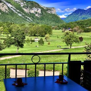 a table with a view of a field and mountains at LE BALCON DU GOLF in Giez