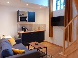 a living room with a blue couch and a kitchen at Hôtes de Saint-Emilion II in Saint-Émilion