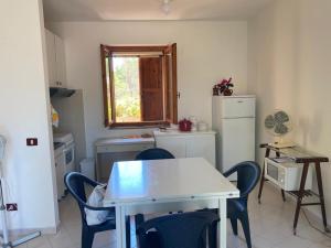 uma cozinha com uma mesa e cadeiras e um frigorífico em Arboria Sun & Sea em Sorso