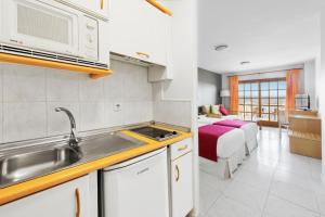 a kitchen with a sink and a microwave in a room at Elba Castillo San Jorge & Antigua Suite Hotel in Caleta De Fuste +32 photos