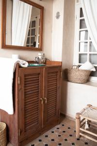 a bathroom with a wooden cabinet and a mirror at Riad Lyon-Mogador in Essaouira