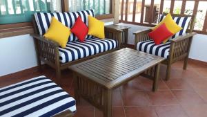 a porch with two chairs and a table with colorful pillows at Duplexe Marina Beach in Restinga Smir