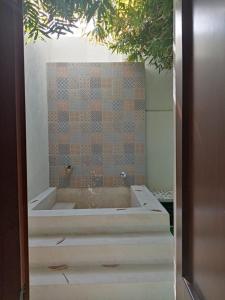 a bath tub in a bathroom with a tiled wall at Hotel Las Monjas in Mérida