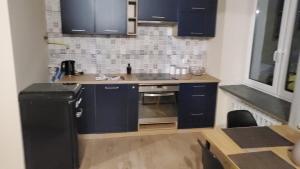 a small kitchen with blue cabinets and a refrigerator at Karpacz Apartament Chabrowy in Karpacz