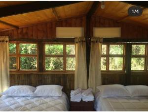 2 łóżka w drewnianym pokoju z oknami w obiekcie Entre Rocas y Cristales w mieście Ráquira