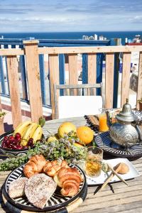 a table with plates of food on a table with the beach at Riad Lyon-Mogador in Essaouira
