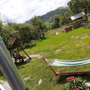 a hammock sitting on a grass field with a hill at Retreat Holiday in Cozy Traditional House in Tarina