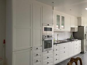 a white kitchen with white cabinets and stainless steel appliances at Casa diatomea in De Haan
