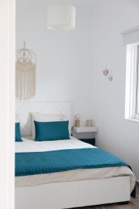 una camera bianca con un grande letto con cuscini blu di Irida's sea front apartment with astonishing view a Theológos