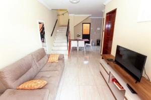 un salon avec un canapé et une télévision à écran plat dans l'établissement Casa Maré Mansa na Praia de Peroba, Maragogi, à Maragogi