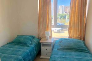 - une chambre avec deux lits à côté d'une fenêtre dans l'établissement PAPUDO - Departamento Frente a la Playa., à Papudo