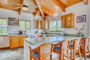 una cocina con armarios de madera y una gran isla con sillas en Kona Kanewa Home en Kailua-Kona